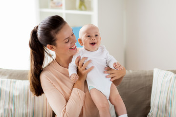 family, motherhood and people concept - happy mother with little baby boy sitting on sofa at home