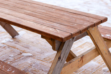 wooden street table and  benches for picnic outdoors in winter on snowy ground