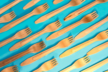 Disposable ecological wooden bamboo forks pattern on a blue background. Environment friendly flat lay