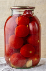 Glass jar of canned tomatoes on a wooden shelf in the cellar