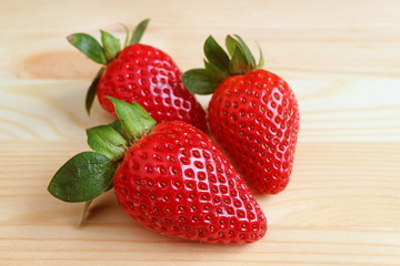 Three of Vibrant Red Fresh Ripe Strawberry Fruits Isolated on Wooden Table