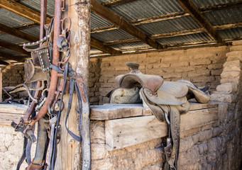 Old dusty western style saddle and horse bridles