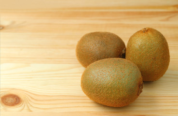 Three of fresh kiwi fruits isolated on wooden table with free space for text and design