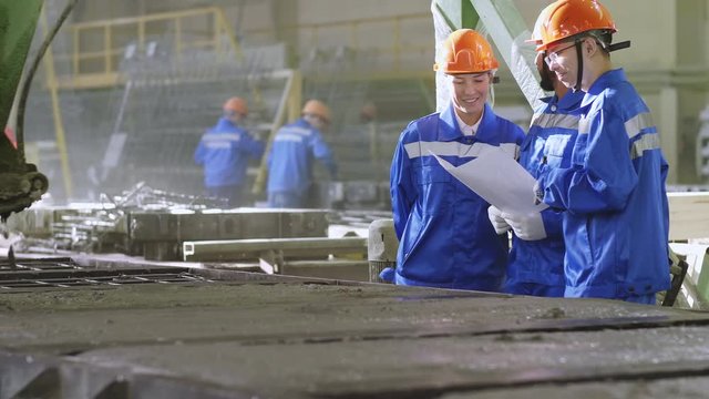 Tilt up shot of international guests visiting ferroconcrete factory for sharing experiences, seeing after machine that grouting forms and exploring documents