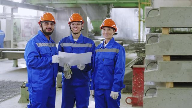 Diverse engineering team staying with scheme at factory, discussing it and then looking to the camera