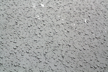 Water drops on grey color car surface.