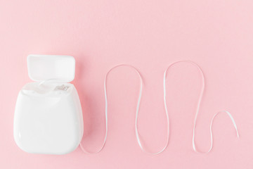 Dental floss on a pink background. The concept of mouth hygiene hygiene, dental health care,...
