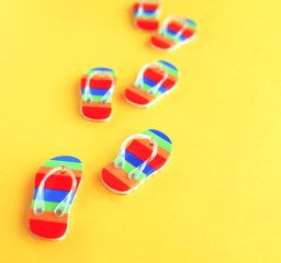 pattern made with colorful summer flip flops toys shoes on bright yellow background top view toned. Minimal summer concept. Copy space