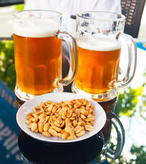 Two glasses of light beer and nuts in the foreground