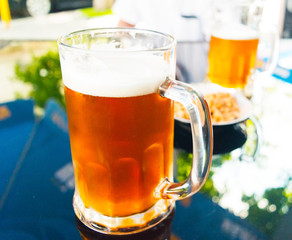 A glass of fresh light and cold beer on a blurred background