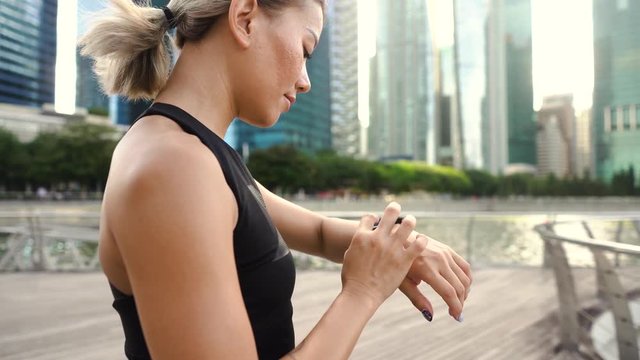 Fitness woman taking a break monitoring progress on smartwatch after difficult training.