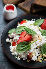 Close-up of salad with strawberry, baby spinach, cottage cheese and peanuts, vertical shot