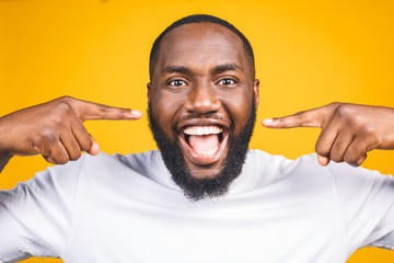 African American man smile. Dental health care isolated against yellow background.