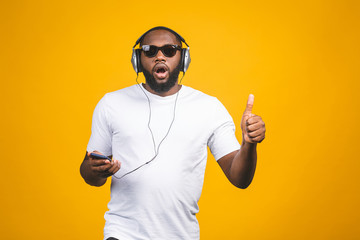 African-American man in casual clothes and headphones listening to music and dancing. Thumbs up.