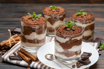 Classic tiramisu dessert in a glass on wooden background