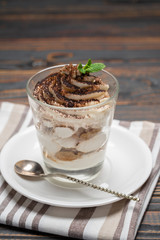 Classic tiramisu dessert in a glass on wooden background