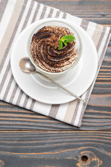 Classic tiramisu dessert in a glass on wooden background