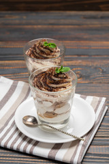 Classic tiramisu dessert in a glass on wooden background