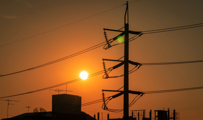 High voltage electric pole and transmission lines in the city. Electricity pylons at sunset. Power...
