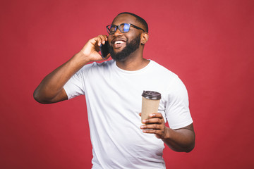 Handsome happy African American with mobile phone and take away coffee cup. Isolated over red background.