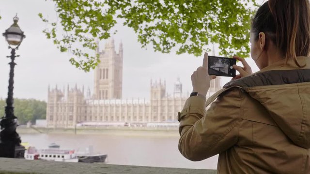 Woman taking picture of a House of Parliament in London