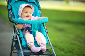 Fototapeta na wymiar little girl in a stroller. baby for a walk in a pram. child in summer outdoors