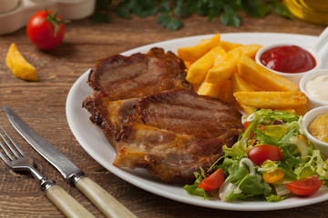 Grilled pork neck served with French fries and salad.