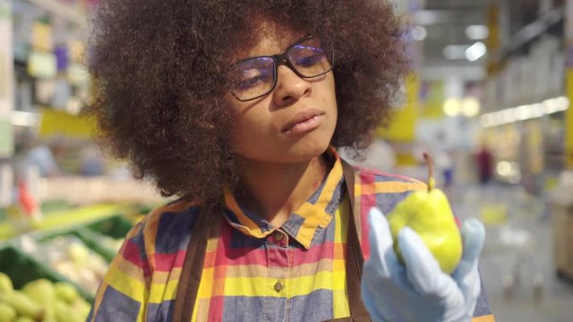 Portrait supermarket employee african american woman with an afro hairstyle sorts the fruit