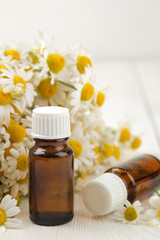 Chamomile. Medicinal little flowers of chamomile with aroma oils on a white wooden table. close-up