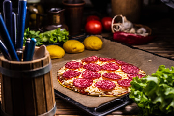 Raw pizza with cheese and salami