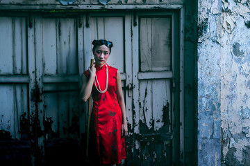 Fototapeta na wymiar Portrait images of Girl wearing red Cheongsam dress Standing and holding a broom For cleaning with old window and wall background, to instagram concept.