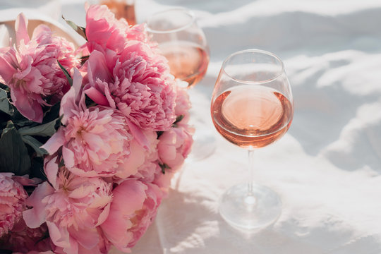 Two glasses of rose wine and peony bouquet on the sunset picnic.