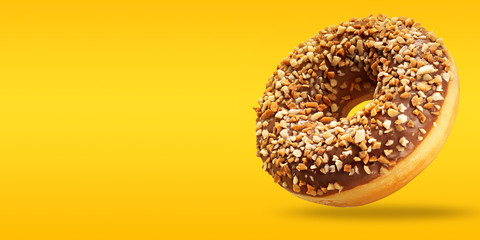 Creative layout made of chocolate donut in flying with copy space on yellow and orange background....