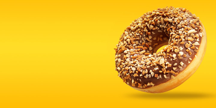 Creative layout made of chocolate donut in flying with copy space on yellow and orange background. Sweet food poster. Minimal concept.