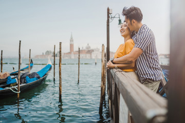 Loving couple in Venice, Italy - Millennials relaxing on the gondola platform in the city - Asian young people on vacation in Italy © loreanto