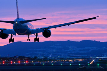 夕焼けの中で着陸する旅客機