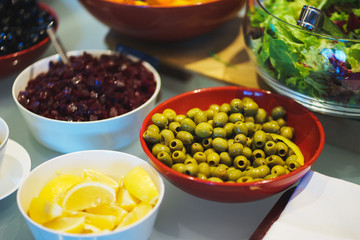 Fresh vegetables, herbs, olives, sauce and salad dressing at the counter. 