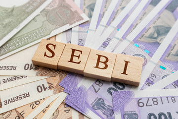 SEBI in wooden block letters on Indian Currency.