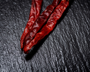 Dried Mexican Red Chile De Arbol Pepper on black natural stone background. Capsicum annuum.