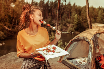 Delighted happy woman trying a tasty tomato