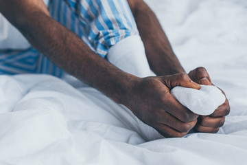 selective focus of african american man suffering from foot pain in bedroom