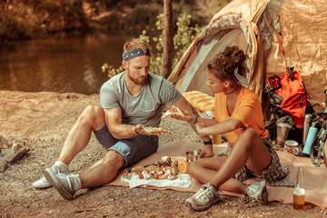 Pleasant hungry young people holding tasty sandwiches