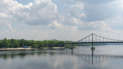 Pedestrian bridge over the dnepr river and the sandy beach in Kiev in the summer day. Panoramic view