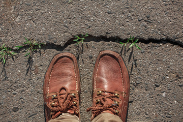 Man in moccasins on cracked asphalt road