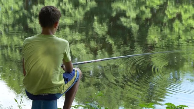 teen child catches a fishing rod on the pond.