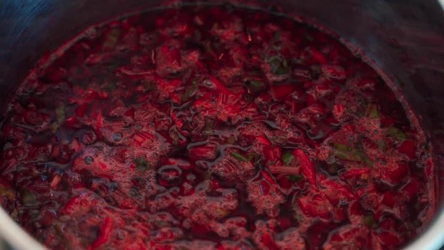Closeup of burgundy boiling beetroot soup in pot.