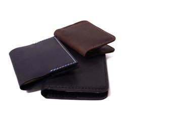 Handmade leather brown cardholder, blue passport cover and black purse isolated on white background closeup. Stock photo of isolated handmade luxury accessories.