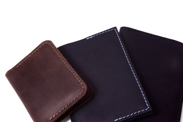 Handmade brown cardholder, blue passport cover and black purse isolated on white background closeup. Stock photo of isolated handmade luxury accessories.