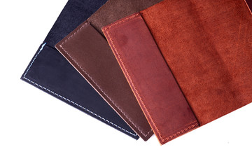 Three handmade leather passport covers isolated on white background. Closeup view. Covers are dark blue, red, brown and opened.