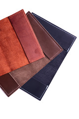 Three handmade leather passport covers isolated on white background. Closeup view. Covers are dark blue, red, brown and opened.